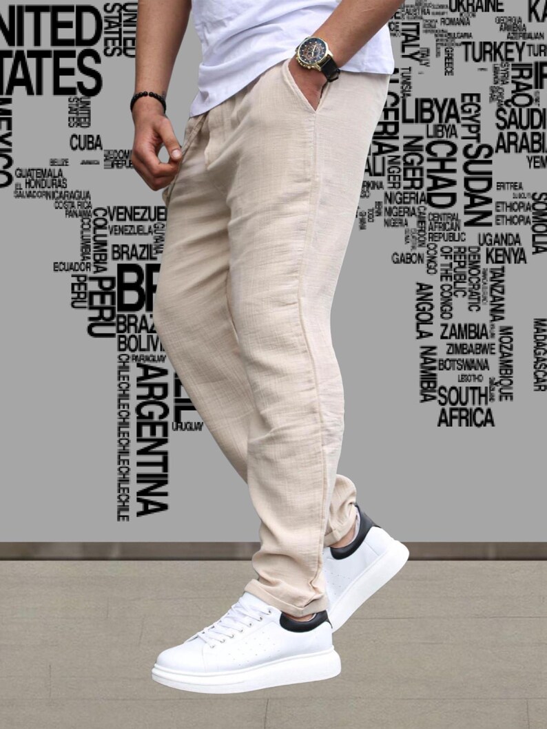 May include: Beige linen pants with a drawstring waist and side pockets. The pants are paired with white sneakers with black accents. The background features a world map design.