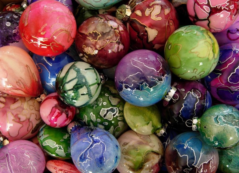 May include: A collection of colorful glass ornaments with intricate patterns and designs. The ornaments are a mix of round and teardrop shapes, and they are all decorated with swirls and lines of silver paint.