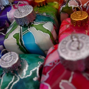 May include: A collection of colorful glass ornaments with intricate designs. The ornaments are decorated with various colors, including green, blue, red, and white. The ornaments are perfect for adding a touch of whimsy to any Christmas tree.