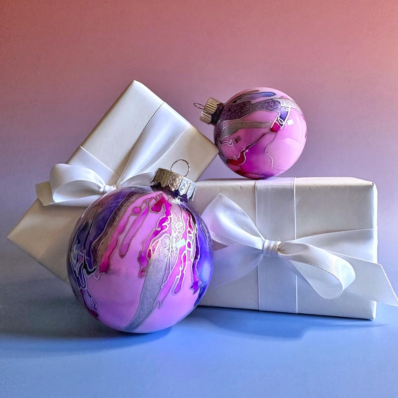 Choose a colorful, hand-painted Christmas ornament dripping with bright pink and purple swirled with silver highlights. Created by Sarah John Afana for schemata on Etsy.