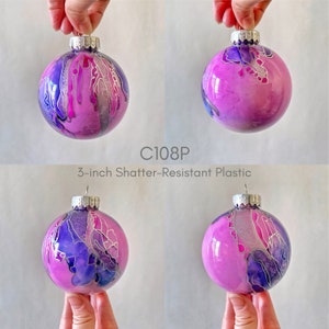 May include: Four 3-inch shatter-resistant plastic ornaments with a pink, purple, and silver abstract design.  C108P