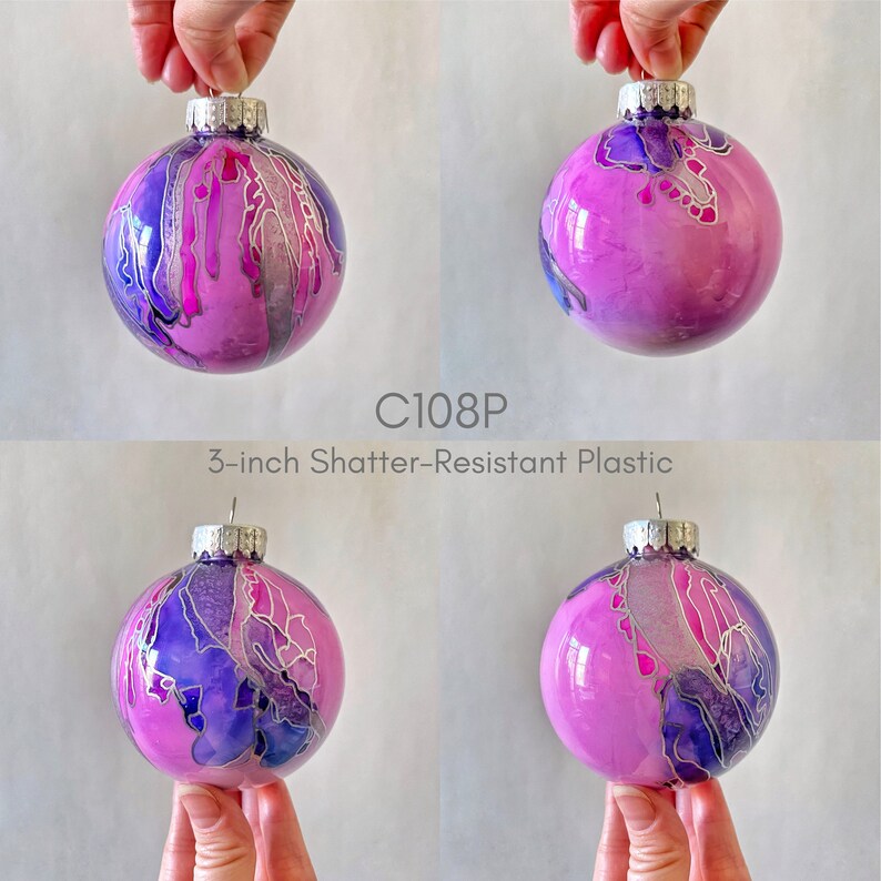May include: Four 3-inch shatter-resistant plastic ornaments with a pink, purple, and silver abstract design.  C108P