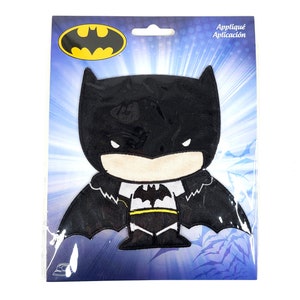 May include: A black and yellow iron-on patch featuring a cartoon version of Batman. The patch is on a blue and white background with the text "Appliqué Aplicación".