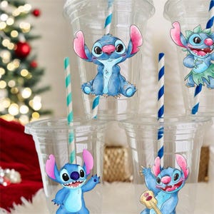 May include: Four clear plastic cups with blue and white striped straws. Each cup has a different blue and pink cartoon character sticker of Stitch from Lilo & Stitch. The stickers show Stitch in different poses, including playing a ukulele.