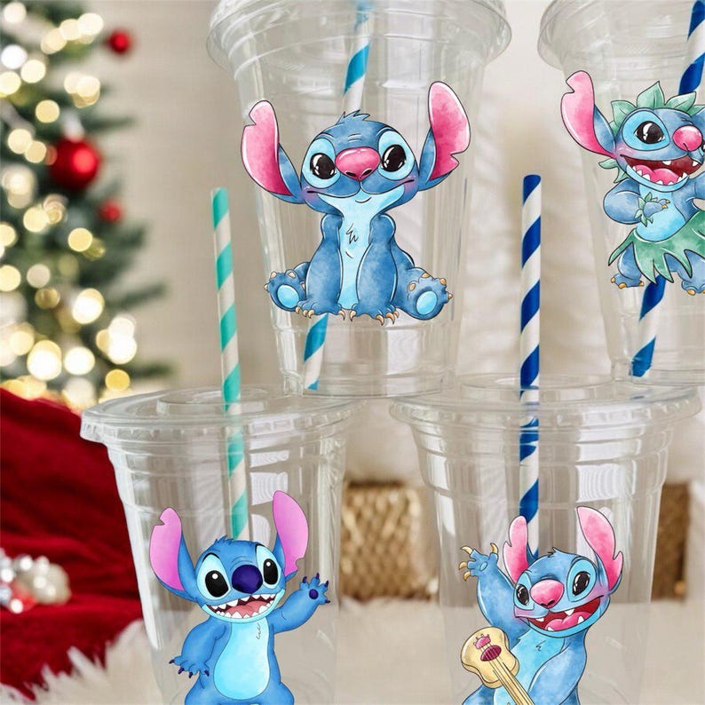 May include: Four clear plastic cups with blue and white striped straws. Each cup has a different blue and pink cartoon character sticker of Stitch from Lilo & Stitch. The stickers show Stitch in different poses, including playing a ukulele.