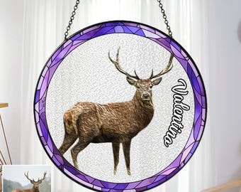 May include: A stained glass window hanging with a purple and white design featuring a deer with large antlers. The name "Valentina" is written in white on the right side of the window.