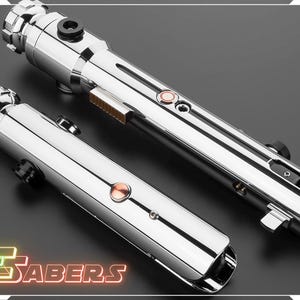 Puede incluir: Dos sables de luz cromados pulidos con detalles met&aacute;licos y botones de color cobre. Los sables de luz se muestran sobre una superficie oscura, con el texto "TSABERS" en una fuente de estilo ne&oacute;n en la esquina inferior izquierda.