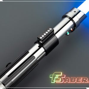 May include: A silver and black lightsaber with a bright blue blade. The hilt features a series of buttons and lights. The image includes the text "TSABERS" in a neon-style font.