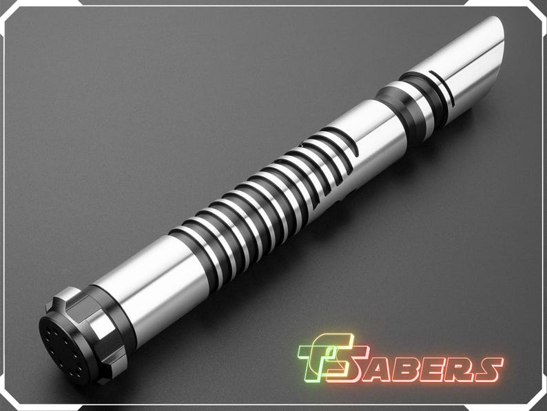 Puede incluir: Un sable de luz plateado y negro con un dise&ntilde;o de empu&ntilde;adura acanalada y un emisor biselado. El sable de luz tiene un pomo negro y una hoja plateada. El logotipo "TSabers" est&aacute; en la esquina inferior derecha.