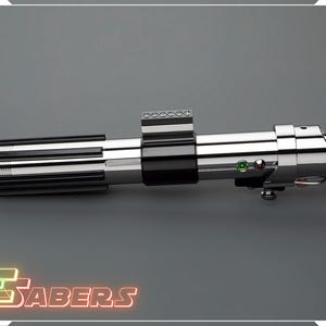 May include: A metallic silver and black lightsaber prop with a detailed design. The lightsaber features a ribbed handle, a black center section, and a silver emitter. The image includes the text "TSABERS" in a neon-style font.