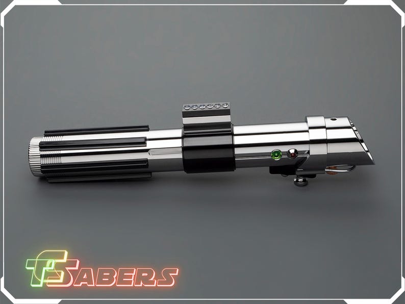 May include: A metallic silver and black lightsaber prop with a detailed design. The lightsaber features a ribbed handle, a black center section, and a silver emitter. The image includes the text "TSABERS" in a neon-style font.