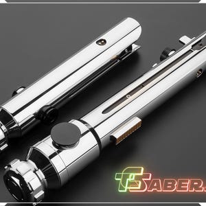 Puede incluir: Dos sables de luz cromados con detalles intrincados, acentos negros y un dise&ntilde;o met&aacute;lico elegante. Los sables de luz tienen un cuerpo cil&iacute;ndrico con varios botones e interruptores. La imagen incluye el texto "TSABERS" en una fuente de estilo ne&oacute;n.