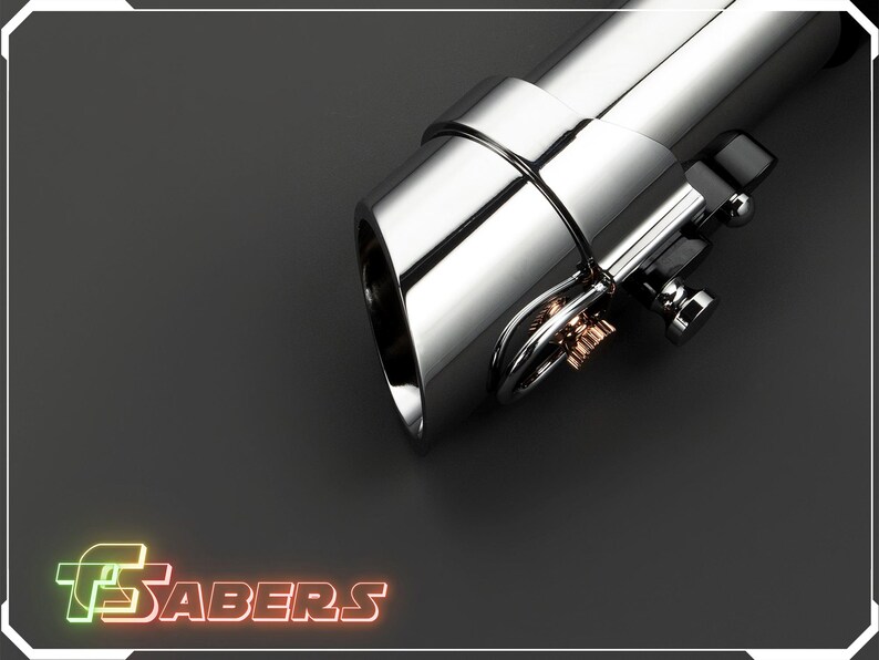 May include: Close-up of a chrome lightsaber hilt with intricate details. The hilt features a polished, reflective surface and a complex design with metallic accents. The image includes the text "TSABERS" in a neon-style font.