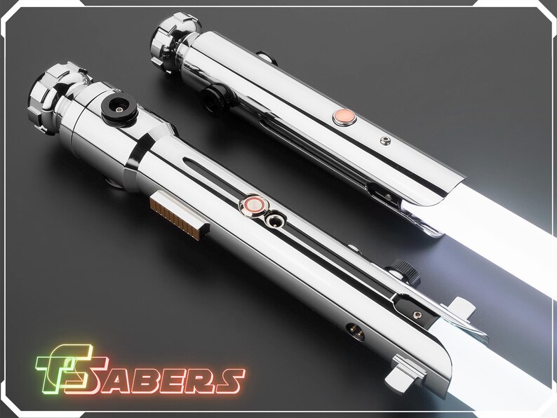 Puede incluir: Dos sables de luz cromados con hojas blancas se muestran en diagonal. Cada sable tiene un mango detallado con botones y una hoja brillante. La imagen incluye el texto "TSABERS" en una fuente de estilo ne&oacute;n.