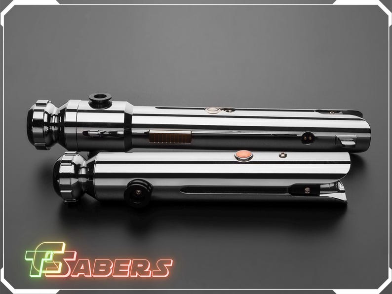 Puede incluir: Dos sables de luz cromados y pulidos se muestran sobre una superficie gris oscuro. Los sables de luz tienen componentes met&aacute;licos detallados, incluyendo botones y empu&ntilde;aduras cil&iacute;ndricas. El logotipo "TSABERS" est&aacute; en la parte inferior de la imagen.