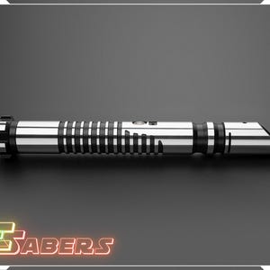 Puede incluir: Un sable de luz plateado y negro con una hoja biselada. El mango presenta bandas negras y plateadas y una serie de l&iacute;neas negras verticales. El producto se muestra sobre un fondo gris oscuro.