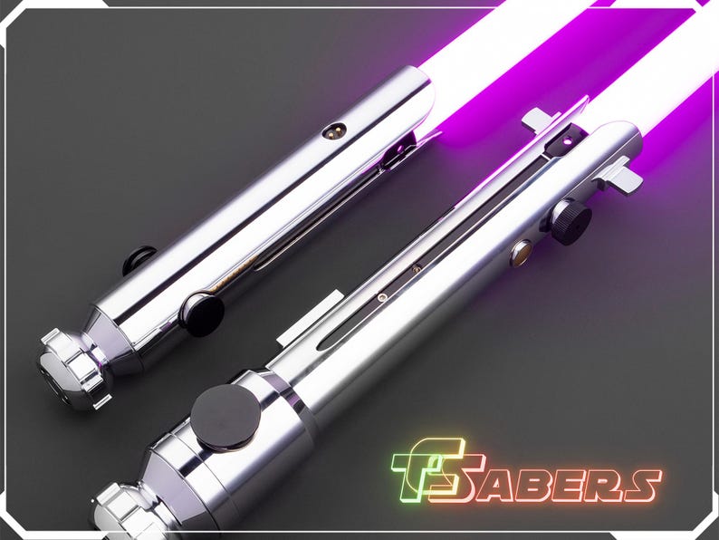 Puede incluir: Dos sables de luz plateados con hojas de color p&uacute;rpura brillante se muestran sobre un fondo oscuro. Los mangos tienen detalles en negro y plata. La imagen incluye el texto "TSABERS" en una fuente de estilo ne&oacute;n.