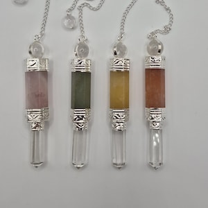May include: Four crystal pendulums with silver-colored metal accents and chains. The pendulums feature a variety of colors, including pink, green, yellow, and orange. Each pendulum has a clear, pointed crystal at the bottom.