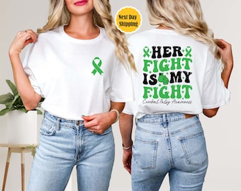 May include: White t-shirt with a green ribbon on the front and the text "HER FIGHT IS MY FIGHT Cerebral Palsy Awareness" on the back.