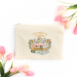 May include: A beige canvas zippered pouch with a floral design and the text "I'd rather be reading".