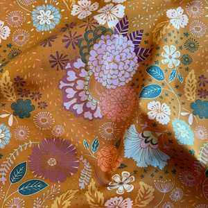 May include: A brown fabric with a floral pattern. The flowers are in shades of pink, purple, blue, and white. The background is a light brown color.