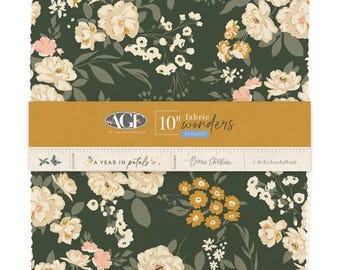 May include: A stack of square fabric pieces featuring a dark green background with cream, yellow, and light pink floral patterns. A mustard yellow paper band wraps around the center, labeled AGF 10 inch fabric wonders 42 pieces A Year in Petals.