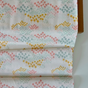 May include: White fabric with a repeating pattern of small, stylized flowers in shades of pink, blue, and yellow. The flowers are arranged in clusters, creating a delicate and whimsical design.