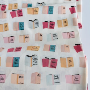 May include: White fabric with a repeating pattern of colorful book covers. The book titles include "The Hobbit", "Anne of Green Gables", "Little Women", "Beloved", "The Wonderful Wizard of Oz", "Black Beauty", and "The Secret Garden".