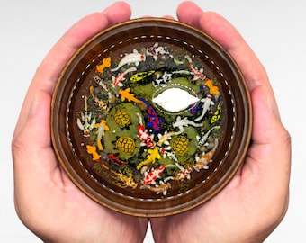 May include: A small wooden bowl filled with a resin art piece depicting a pond scene. The scene includes colorful koi fish, turtles, and green plants. A white cloud is floating in the center of the bowl.