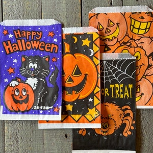 Pu&ograve; includere: Quattro sacchetti per dolcetti di Halloween con diversi design. Un sacchetto &egrave; viola con stelle e dice "Happy Halloween" con un gatto nero e una zucca arancione. Un altro sacchetto &egrave; nero con un ragno e dice "Trick or Treat". Gli altri due sacchetti sono arancioni e neri con zucche e stelle.