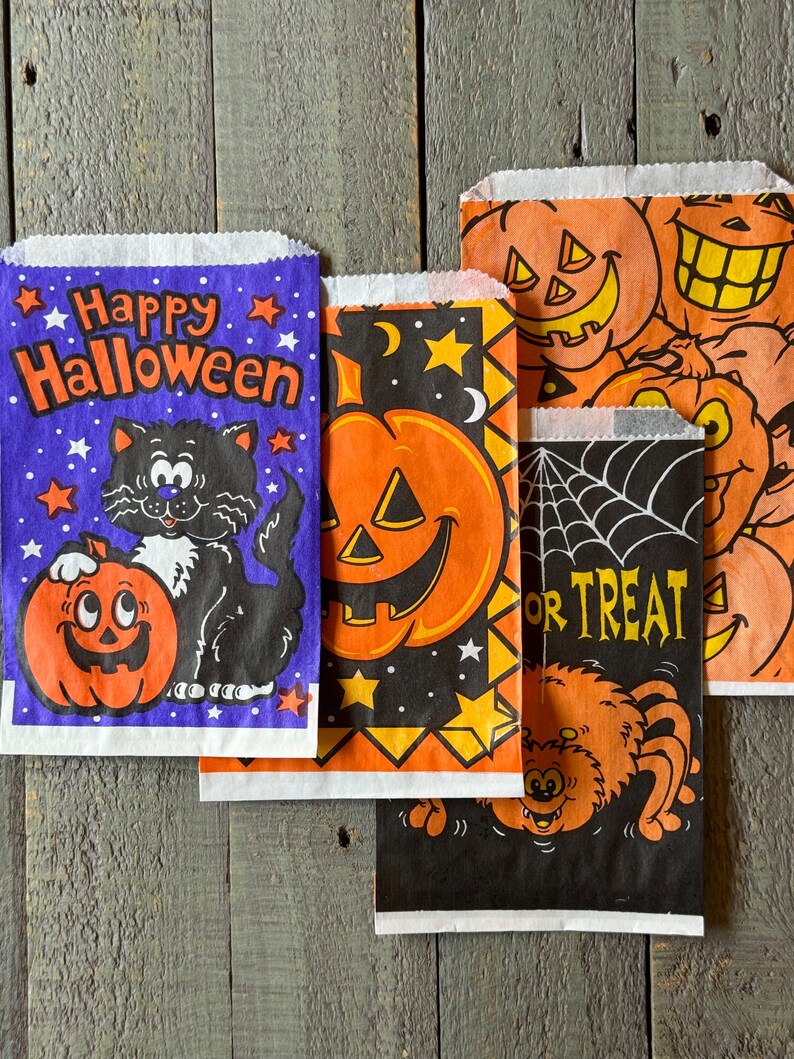 Pu&ograve; includere: Quattro sacchetti per dolcetti di Halloween con diversi design. Un sacchetto &egrave; viola con stelle e dice "Happy Halloween" con un gatto nero e una zucca arancione. Un altro sacchetto &egrave; nero con un ragno e dice "Trick or Treat". Gli altri due sacchetti sono arancioni e neri con zucche e stelle.