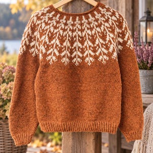 Peut inclure: Un pull en tricot à manches longues de couleur rouille profonde avec une encolure ronde et un empiècement contrastant crème orné d'un motif répétitif en forme de feuilles. Le vêtement possède des poignets et un ourlet côtelés.