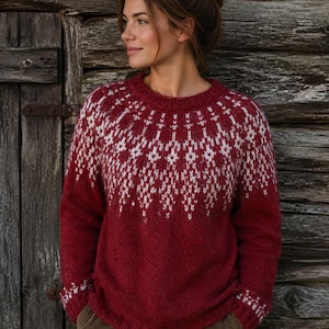 May include: A long-sleeved, crew-neck sweater in a deep red hue, featuring a white, intricate geometric pattern across the yoke and matching white geometric detailing around the ribbed cuffs. The sweater is constructed with a knit texture.