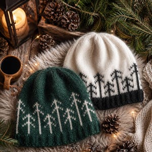 Puede incluir: Dos gorros de punto con un patrón de árboles de bosque. Un gorro es de color verde oscuro con un diseño de árboles claros, y el otro es de color crema con un diseño de árboles oscuros. Ambos tienen un borde acanalado y una corona redondeada.