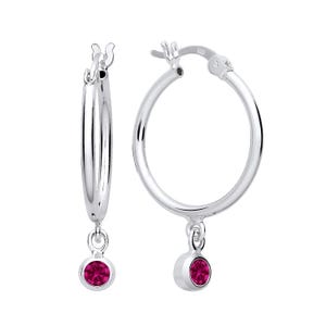 May include: Silver hoop earrings with a dangling pink gemstone.