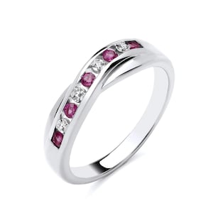 May include: A silver band ring with a row of pink gemstones and smaller white gemstones set in a chevron pattern.