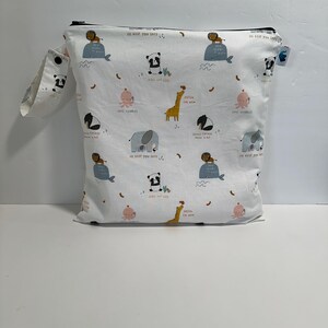 May include: White fabric bag with a black zip and a small handle. The bag is patterned with cartoon animals, including lions, pandas, octopuses, giraffes, and elephants. The bag has the text "I'll keep you safe."