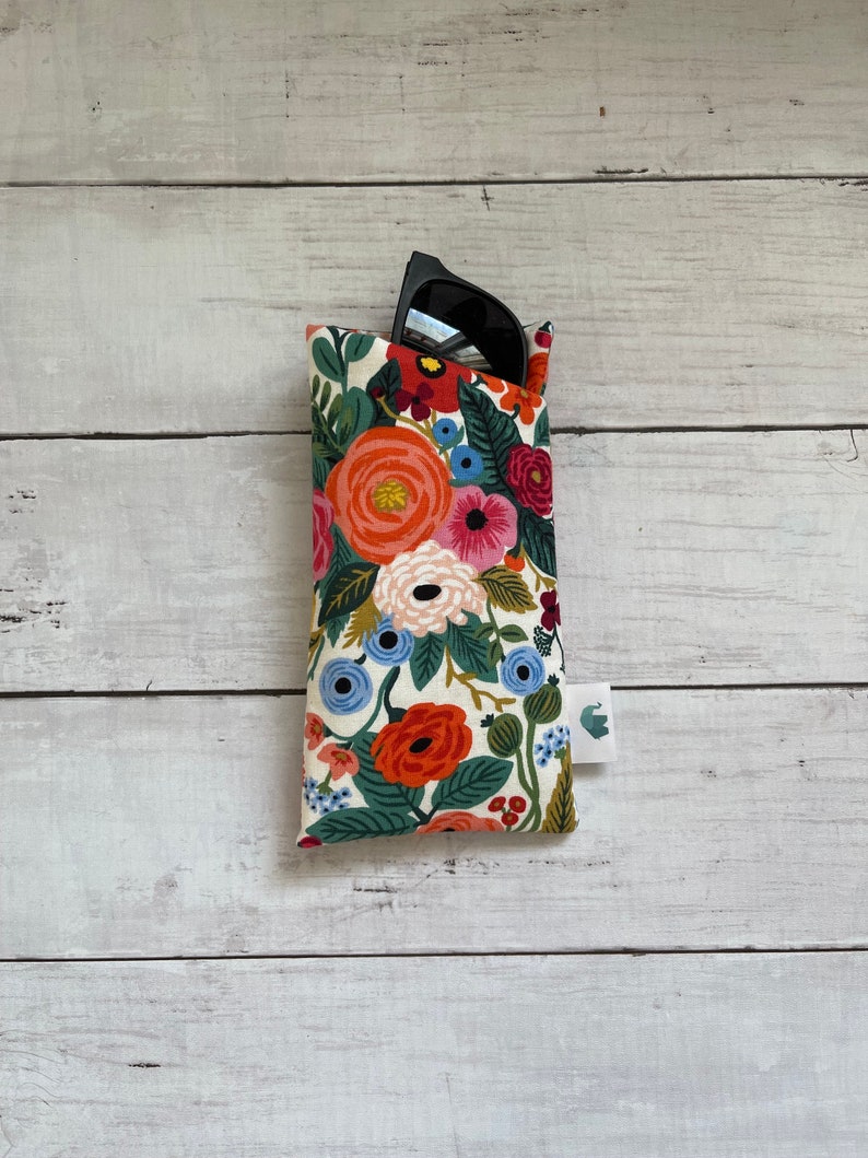 May include: A floral patterned fabric sunglasses case with a pair of black sunglasses inside.