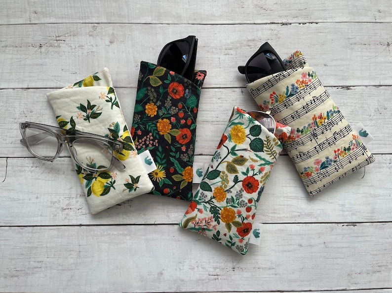 May include: Four different fabric eyeglass cases with floral patterns. The cases are all closed and feature a variety of floral designs, including lemons, flowers, and musical notes.