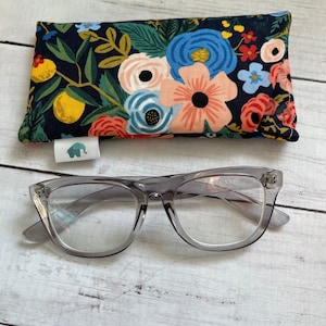 May include: A gray pair of glasses with clear lenses and a floral print eyeglass case. The case has a dark blue background with pink, red, blue, and yellow flowers.
