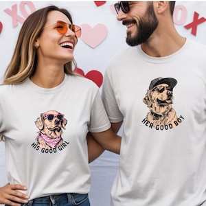 May include: Two matching white t-shirts with dog graphics. One shirt says "His Good Girl" and features a dog wearing sunglasses and a pink bandana. The other shirt says "Her Good Boy" and features a dog wearing sunglasses and a cap.