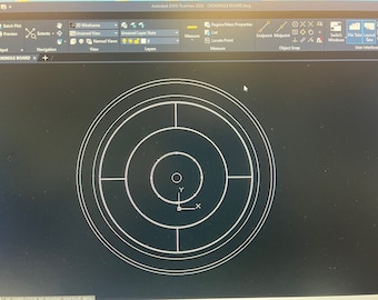 May include: A black and white image of a target with concentric circles and a crosshair in the center. The target is on a black background.