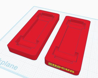 May include: Two red plastic molds for making soap bars. The mold on the right has the text "Shogun" printed on the bottom.