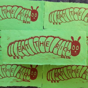 Parche para coser en linograbado "La Oruga Hambrienta": "CÓMETE A LOS RICOS" (6,35 x 19,18 cm)