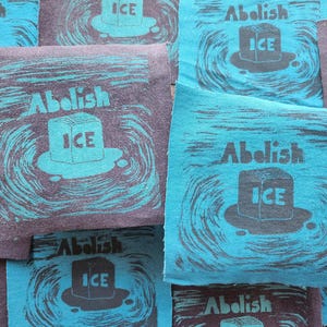 Puede incluir: Una colección de parches de tela cuadrados con un gráfico serigrafiado de un cubo de hielo derritiéndose en un charco. El diseño incluye el texto "Abolish ICE" en una fuente negrita. Los parches están disponibles en dos colores: gris oscuro con tinta verde azulado o verde azulado con tinta gris oscuro.
