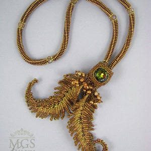 May include: A gold beaded necklace with a large green gemstone pendant. The pendant is shaped like a fern leaf and is made of smaller gold beads.
