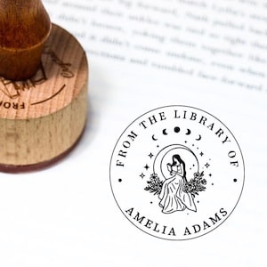 Peut inclure: Illustration en noir et blanc d'une femme lisant un livre sous une lune croissante avec des étoiles. Le texte indique "From the Library of Amelia Adams".