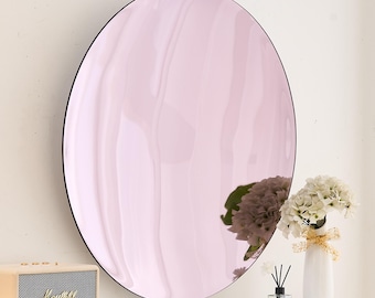 May include: A large round mirror with a pink tinted glass surface. The mirror has a thin black frame.