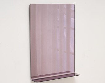 May include: A rectangular, mauve-colored wall shelf with a small, horizontal shelf at the bottom. The shelf is mounted on a white wall. The surface reflects the light and the window behind it.