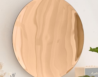 May include: A large, round, copper-colored mirror with a slightly rippled surface. The mirror is hanging on a white wall.
